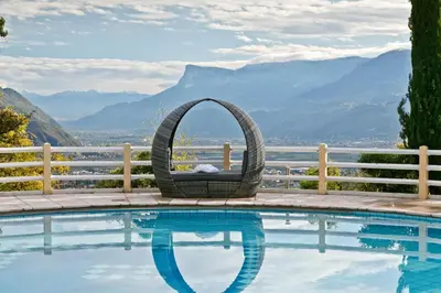 a wicker chair sitting next to a swimming pool at Panorama Vital Hotel Rimmele in Tirolo