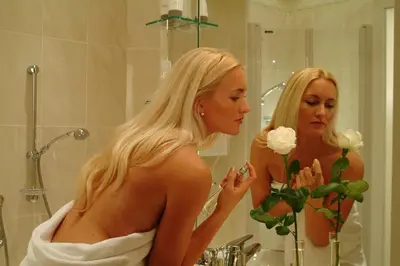 a woman standing in front of a bathroom mirror at Panorama Vital Hotel Rimmele in Tirolo