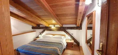 a bedroom with a bed in a room with wooden ceilings at Rustico nelle Dolomiti in Val di Zoldo
