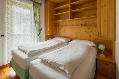 two twin beds in a room with a window at Casa Piva Dolomiti in Val di Zoldo