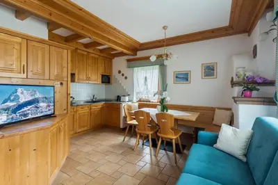 a kitchen and living room with a blue couch and a table at Casa Piva Dolomiti in Val di Zoldo