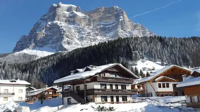 a snow covered mountain in front of a lodge at Casa Piva Dolomiti in Val di Zoldo
