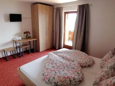 a bedroom with a bed and a table and a window at Zehrehof in Bressanone