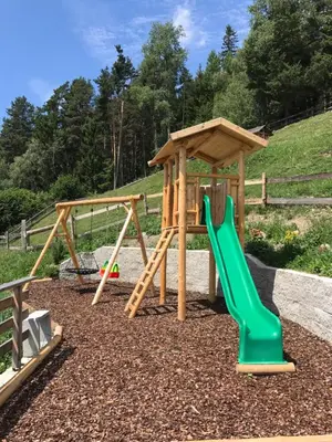 a playground with two swings and a slide at Zehrehof in Bressanone