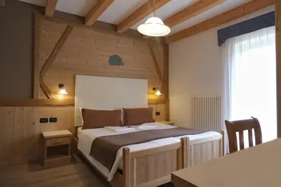 a bedroom with a bed in a room with wooden walls at Flos Hotel in Moena