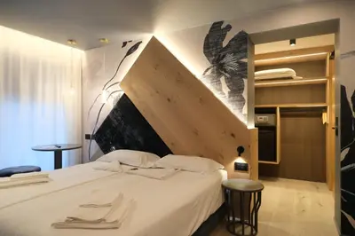 a bedroom with a large white bed with a wooden headboard at Flos Hotel in Moena