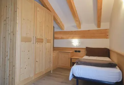 a small room with a bed and a desk at Flos Hotel in Moena