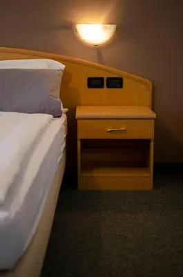 a hotel room with a bed and a nightstand with a bed sidx sidx sidx at Flos Hotel in Moena