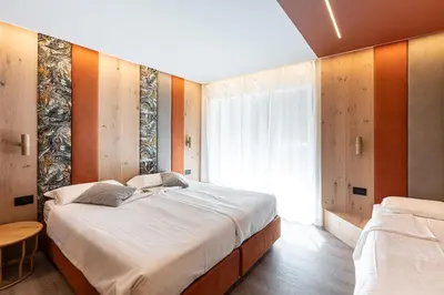 a bedroom with a large bed and a window at Flos Hotel in Moena