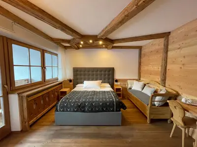 a bedroom with a bed and a couch in it at Agriturismo Maso Corradini in Castello di Fiemme