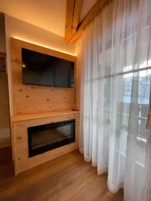 a living room with a fireplace and a flat screen tv at Agriturismo Maso Corradini in Castello di Fiemme