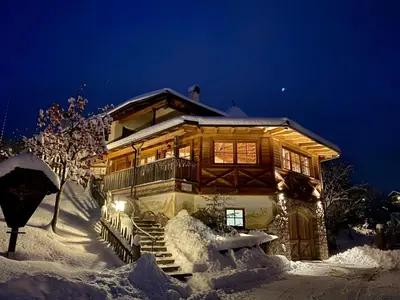 a log cabin in the snow at night at Agriturismo Maso Corradini in Castello di Fiemme