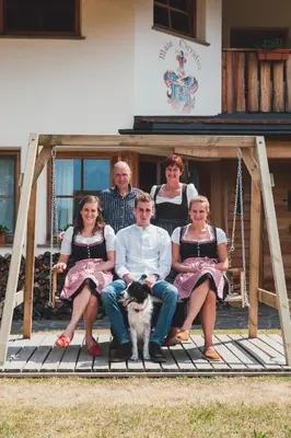 a group of people sitting on a porch with a dog at Agriturismo Maso Corradini in Castello di Fiemme