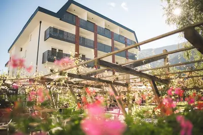 a building with pink flowers in front of it at Park Hotel Villa Etschland in Plaus