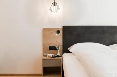 a bedroom with a bed with a black headboard and a table at Park Hotel Villa Etschland in Plaus