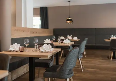 a restaurant with wooden tables and chairs with wine glasses at Park Hotel Villa Etschland in Plaus
