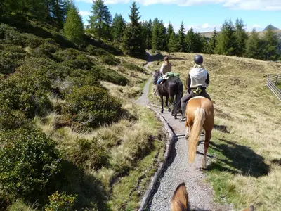 two people riding horses down a dirt road at Reiterhof Edelweiss in San Genesio Atesino