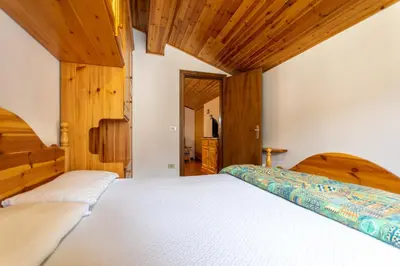 two beds in a bedroom with wooden ceilings at Chalet Catinaccio in Soraga