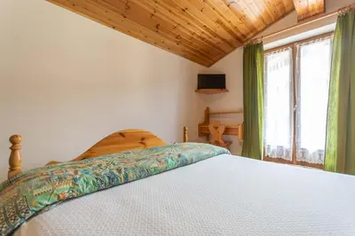 a bedroom with a white bed and a window at Chalet Catinaccio in Soraga