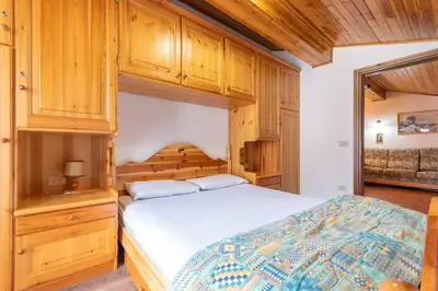 a bedroom with a bed and wooden cabinets at Chalet Catinaccio in Soraga