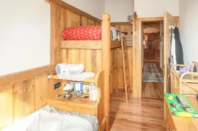 a room with a bunk bed and a wooden floor at Tabià Elisa in Campitello di Fassa