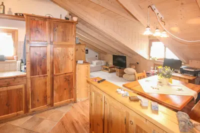 a kitchen with wooden cabinets and a living room at Tabià Elisa in Campitello di Fassa