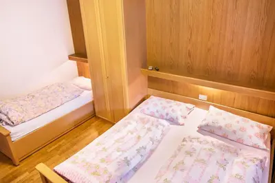 two beds in a small room with wooden walls at Casa Matie in Selva di Val Gardena