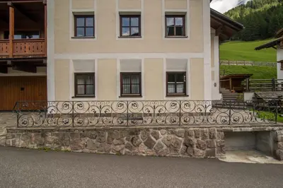 a house with a stone wall and a fence at Casa Matie in Selva di Val Gardena