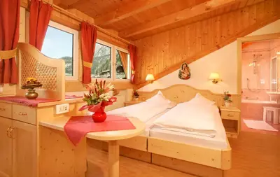 a bedroom with a bed and a table with flowers on it at Garni B&B Schenk in Selva di Val Gardena