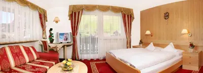 a hotel room with a bed and a chair at Garni B&B Schenk in Selva di Val Gardena