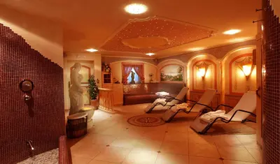 a bathroom with a room with chairs and a tub at Garni B&B Schenk in Selva di Val Gardena