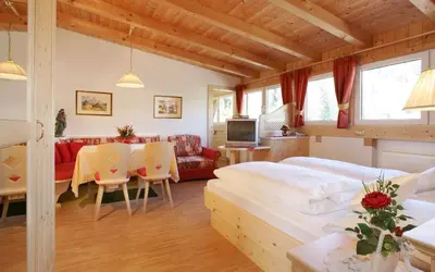a bedroom with a bed and a living room at Garni B&B Schenk in Selva di Val Gardena