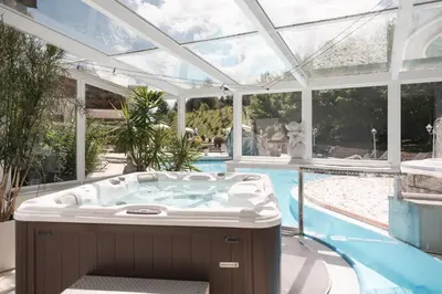 a hot tub in a conservatory next to a swimming pool at Hotel Sonklarhof in Ridanna