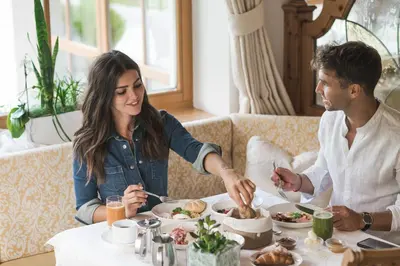 a man and woman sitting at a table eating food at Hotel Sonklarhof in Ridanna