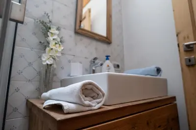 a bathroom sink with towels on a wooden counter at Mountain Dolomiti Apartments-Maison Perrod in Predazzo