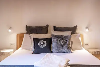 a bedroom with a white bed with pillows at Mountain Dolomiti Apartments-Maison Perrod in Predazzo