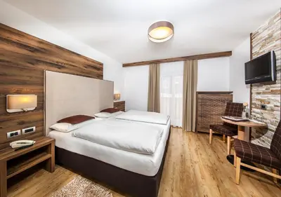 a bedroom with a bed and a desk and a tv at Garni Lanzinger in Selva di Val Gardena