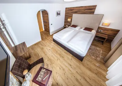 a bedroom with a large bed and a wooden floor at Garni Lanzinger in Selva di Val Gardena