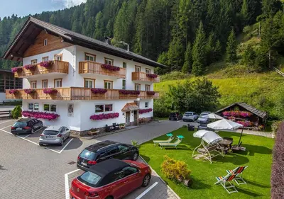 a large building with cars parked in a parking lot at Garni Lanzinger in Selva di Val Gardena