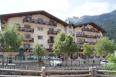 a large building with cars parked in front of it at Albergo Alla Rosa in Canazei