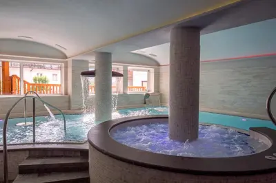 a large indoor pool with a hot tub in a house at Albergo Alla Rosa in Canazei