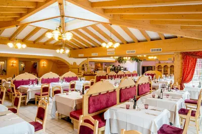 a dining room with white tables and purple chairs at Albergo Alla Rosa in Canazei