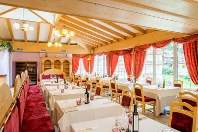 a dining room with white tables and chairs at Albergo Alla Rosa in Canazei