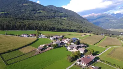 a building with a lawn with chairs in front of it at Appartement- und Wellnesshotel Winkler in Falzes