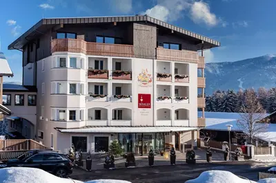 a hotel in the mountains with mountains in the background at Appartement- und Wellnesshotel Winkler in Falzes