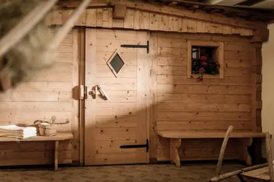 a wooden shed with a bench next to a table at Appartement- und Wellnesshotel Winkler in Falzes