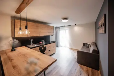 a kitchen with a wooden table and a couch at Appartement- und Wellnesshotel Winkler in Falzes