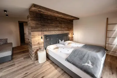 a bedroom with a large bed with a wooden wall at Appartement- und Wellnesshotel Winkler in Falzes