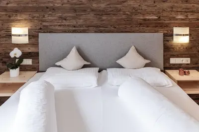 a large white bed with two pillows on it at Appartement- und Wellnesshotel Winkler in Falzes