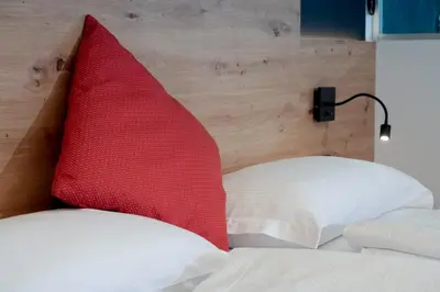 a red pillow sitting on top of a bed at Dolomiten Hotel Irma in Canazei